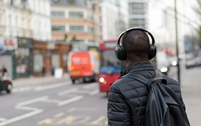 Person wearing headphones walking on busy city street