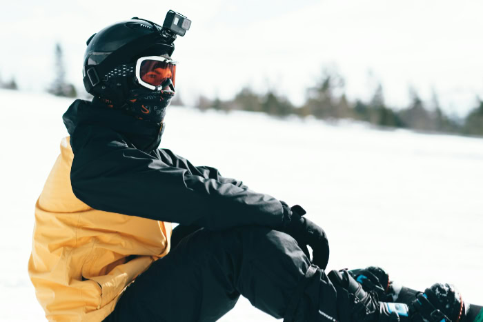 Person wearing helmet with GoPro while snowboarding