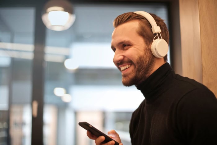 Person wearing white headphones holding a smartphone