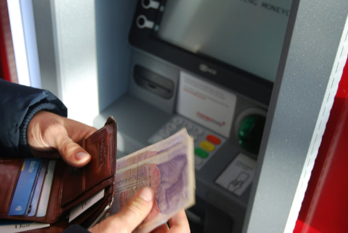 Person withdrawing pound banknotes from an ATM