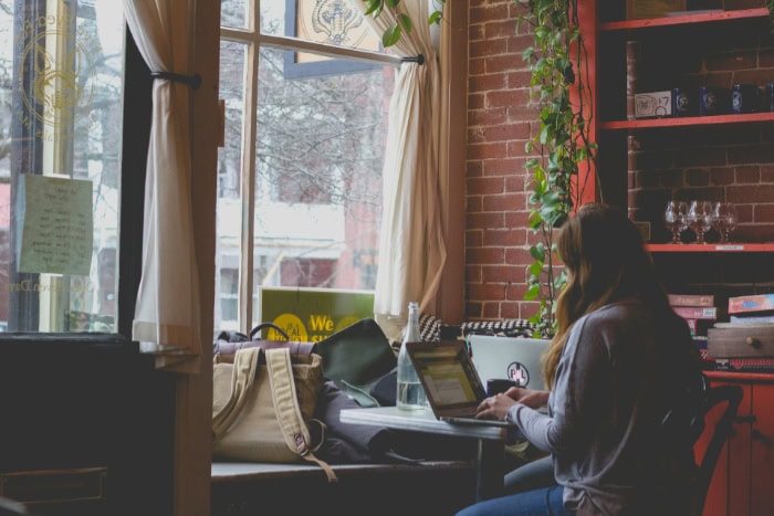 Person working on laptop in cozy cafe with brick walls