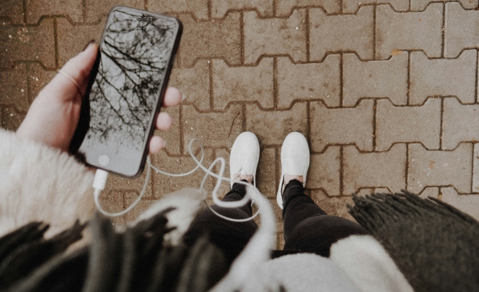 Persons legs in white sneakers holding smartphone