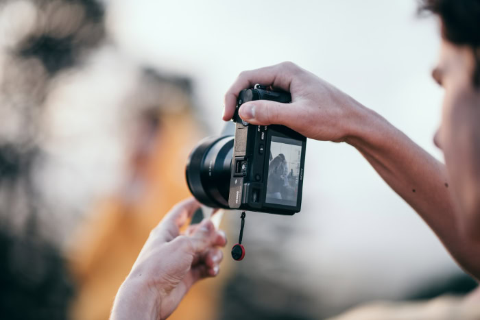 Photographer holding mirrorless camera taking outdoor photo