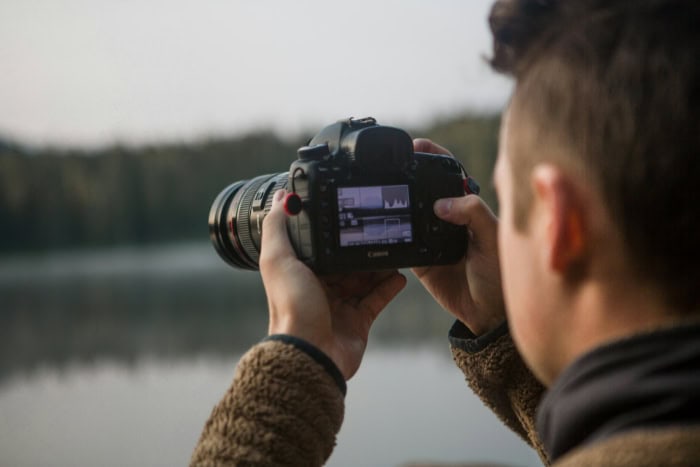 Photographer using DSLR camera to capture lake landscape