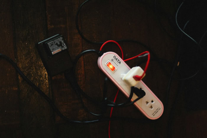 Pink power strip with tangled cords on floor