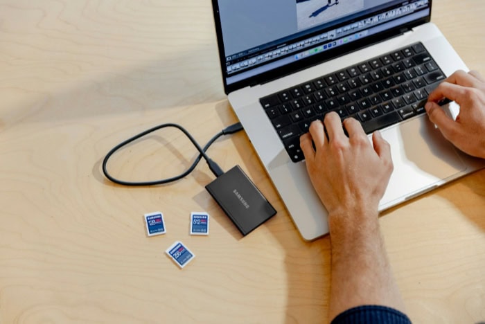 Portable SSD connected to a laptop with SD cards nearby