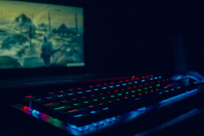 RGB lit gaming keyboard with a blurred screen in the background