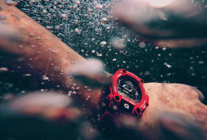 Red G Shock sport watch worn underwater with bubbles