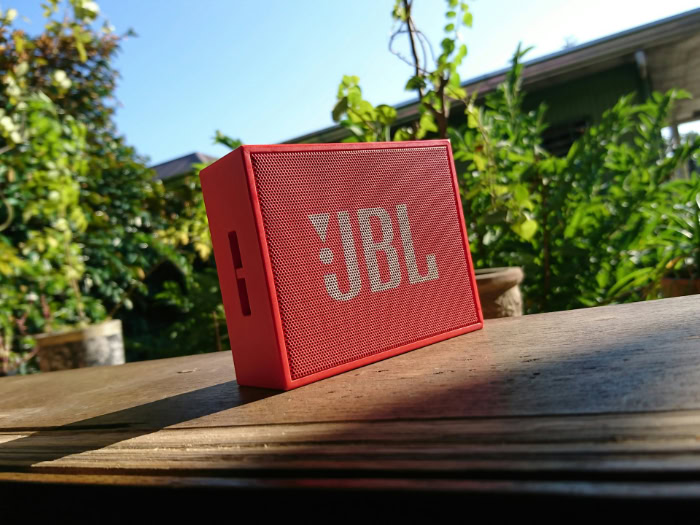 Red JBL GO portable Bluetooth speaker outdoors