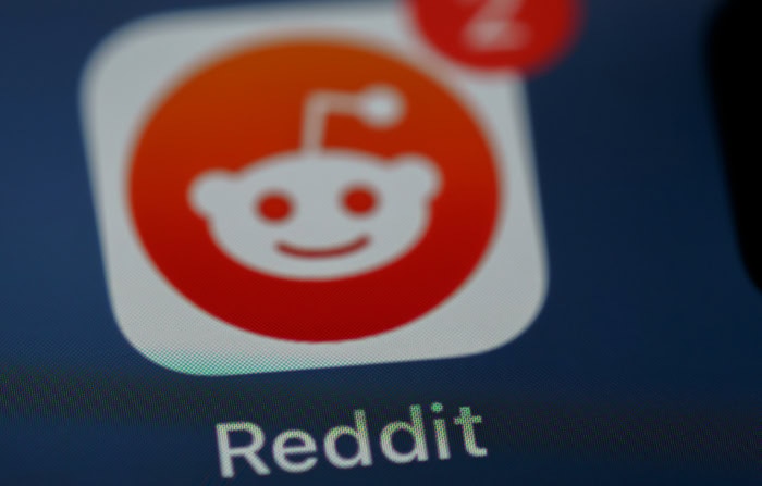 Reddit app icon with smiling alien logo on smartphone screen