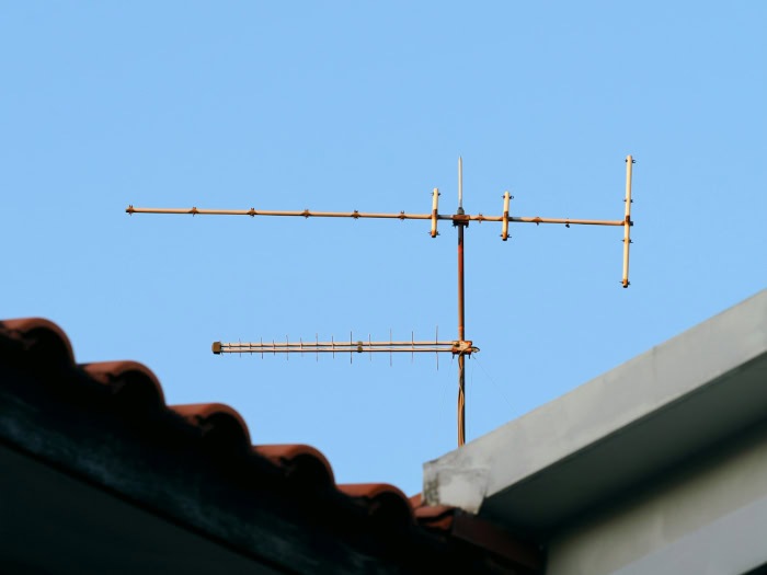 Rooftop television antenna mounted against clear blue sky