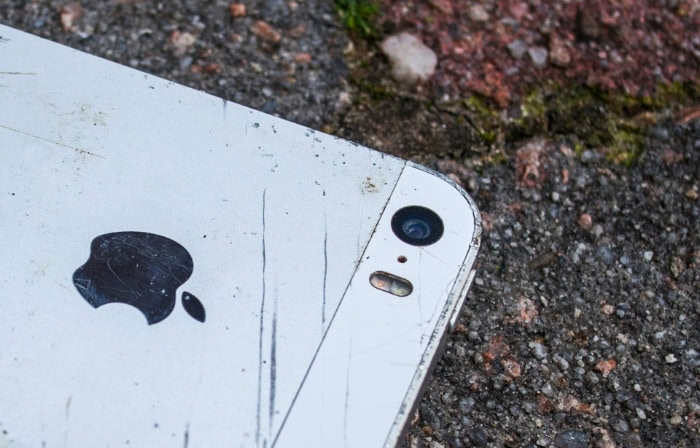 Scratched and damaged white iPhone on rough concrete surface