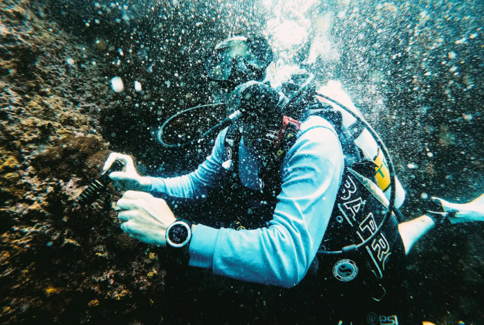Scuba diver wearing dive watch underwater with bubbles