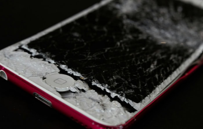 Severely cracked iPhone screen with damaged home button