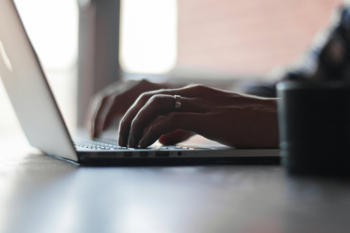 Side view of hands typing on laptop keyboard resized