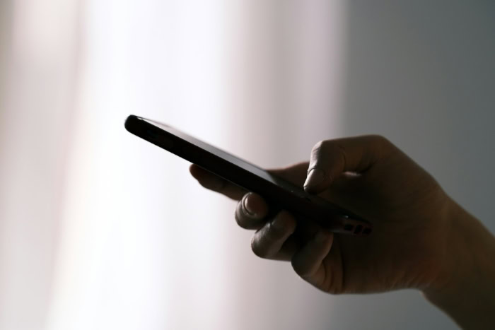Silhouette of a hand holding a mobile phone