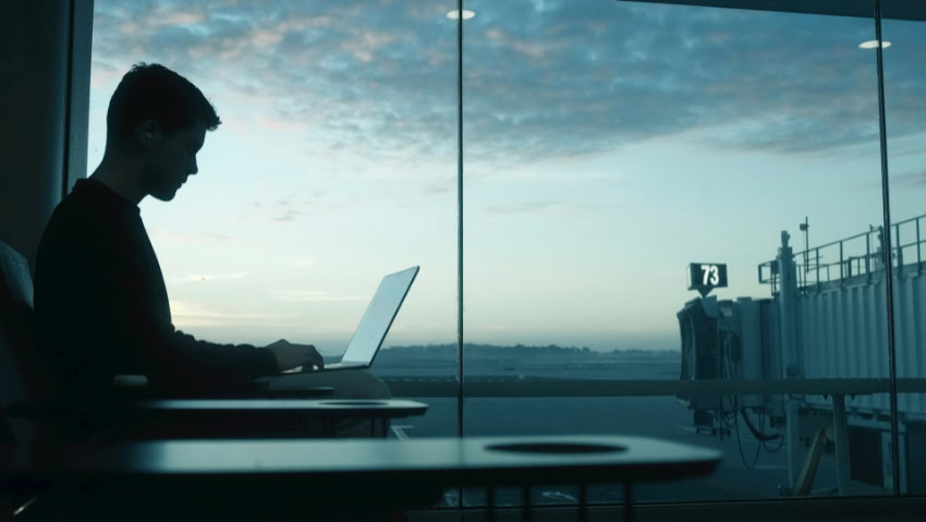 Silhouette of man using laptop at airport terminal