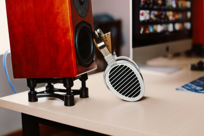 Silver headphones leaning against a wooden speaker
