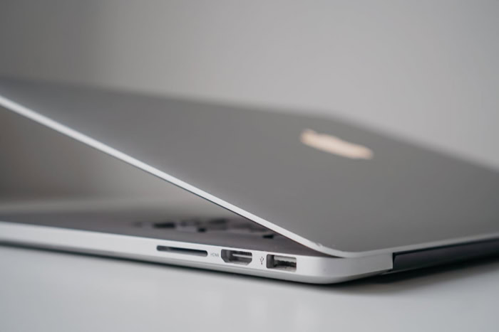 Silver macbook half open showing ports and slim design