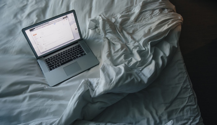 Silver macbook in bed