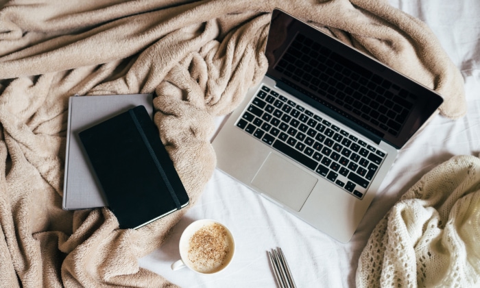 Silver macbook near coffee mug in bed