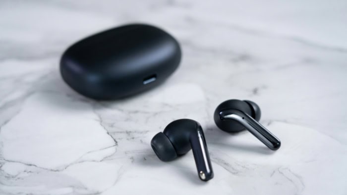 Sleek black wireless earbuds beside case on marble