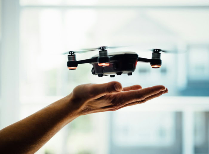 Small drone hovering above an open palm indoors