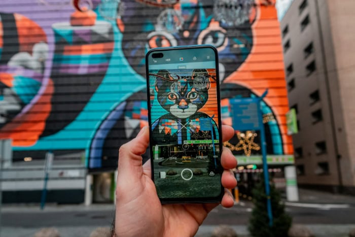 Smartphone camera capturing colorful cat street art mural