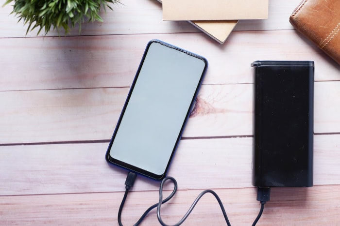 Smartphone charging with black power bank on wooden desk