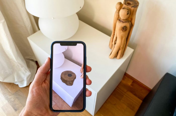 Smartphone displaying AR overlay of a wooden object