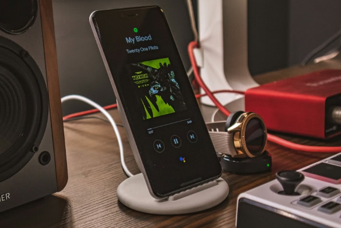 Smartphone displaying Spotify on wireless charging stand