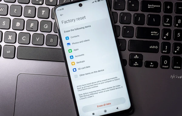 Smartphone displaying factory reset menu on laptop keyboard