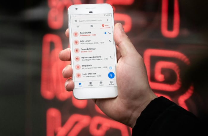 Smartphone displaying spam call list with red neon sign background