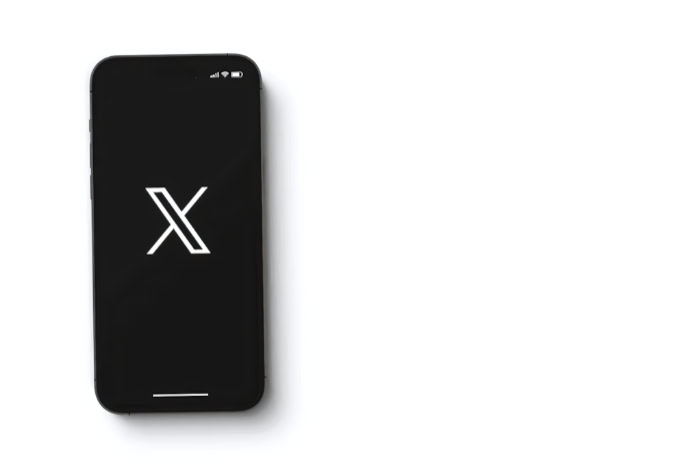 Smartphone displaying white X logo on black screen