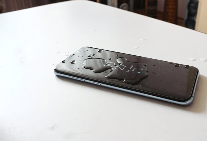 Smartphone on white table covered in water droplets