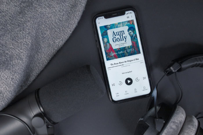 Smartphone playing audiobook next to microphone and headphones