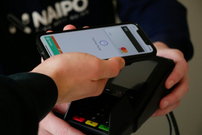 Smartphone tapping a payment terminal via Apple Pay