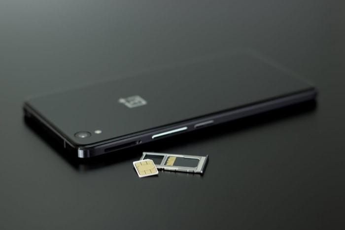 Smartphone with SIM card and tray on black surface