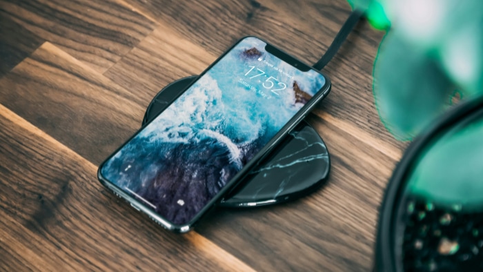 Smartphone with an ocean wallpaper on a black marbled wireless charger