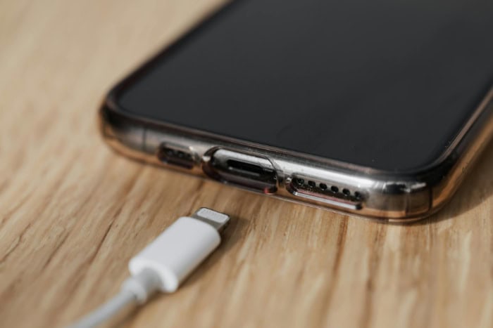 Smartphone with charging cable placed on wooden surface