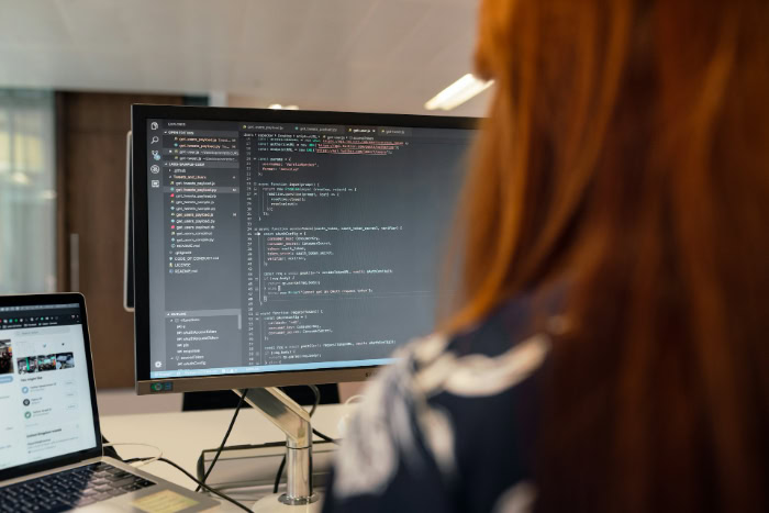 Software developer coding on a large computer monitor