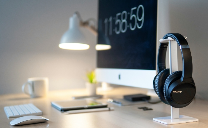 Sony headphones on a stand beside an iMac on a desk