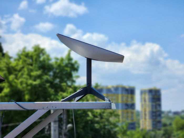 Starlink satellite dish mounted outdoors with city background