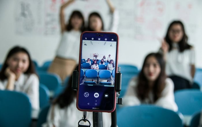 Students posing for group photo captured on smartphone screen