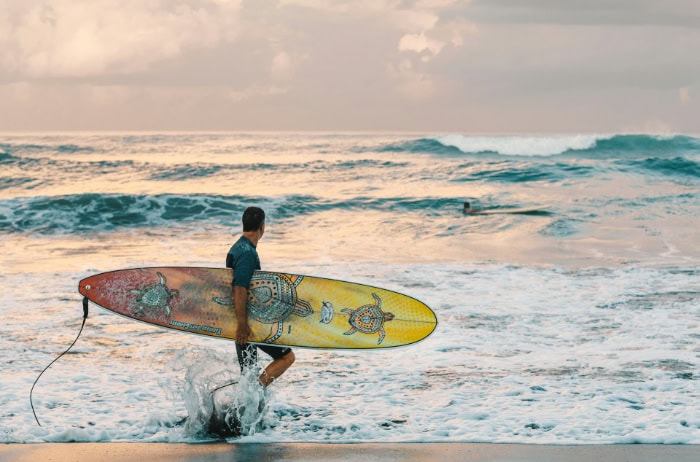 Surfer with colorful board walking toward the ocean