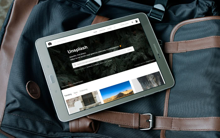 Tablet displaying Unsplash website with nature photography