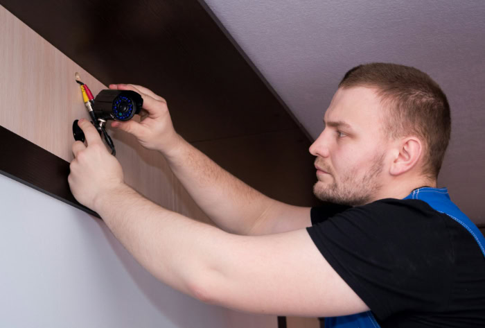 Technician installing indoor CCTV security camera on wall
