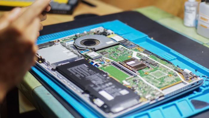Technician repairing exposed internal components of a laptop