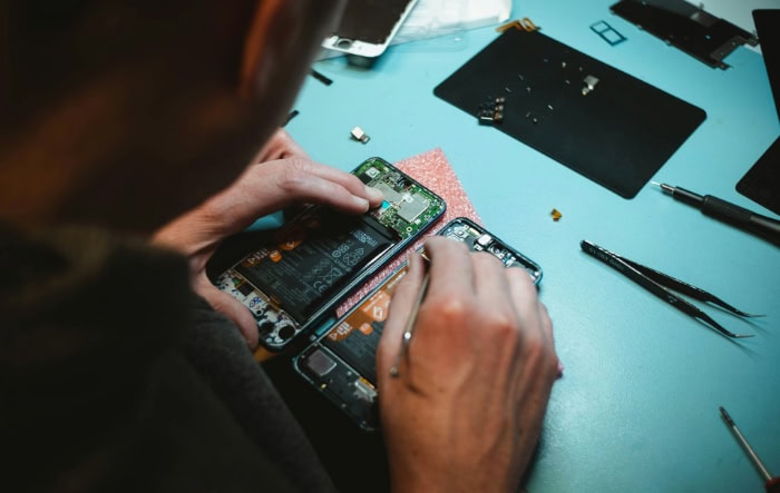 Technician repairing smartphone on blue surface