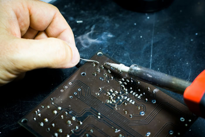 Technician soldering an electronic circuit board component